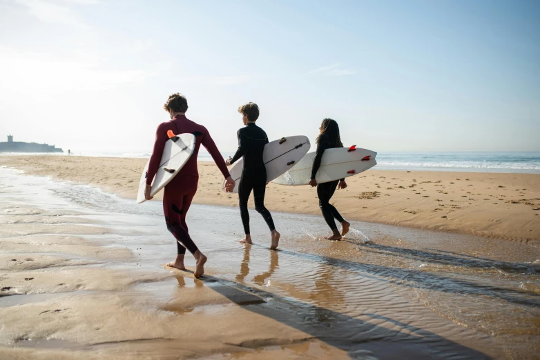 three people walking on a beach with surfboards, by Nina Hamnett, pexels contest winner, teenage boy, manuka, 1 4 9 3, cast