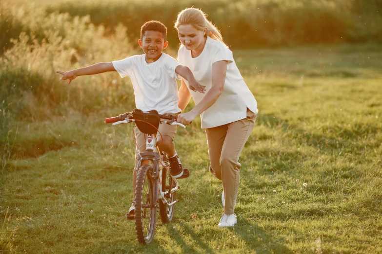 a young boy riding a bike next to a woman, pexels contest winner, symbolism, all overly excited, summer morning, brown, white