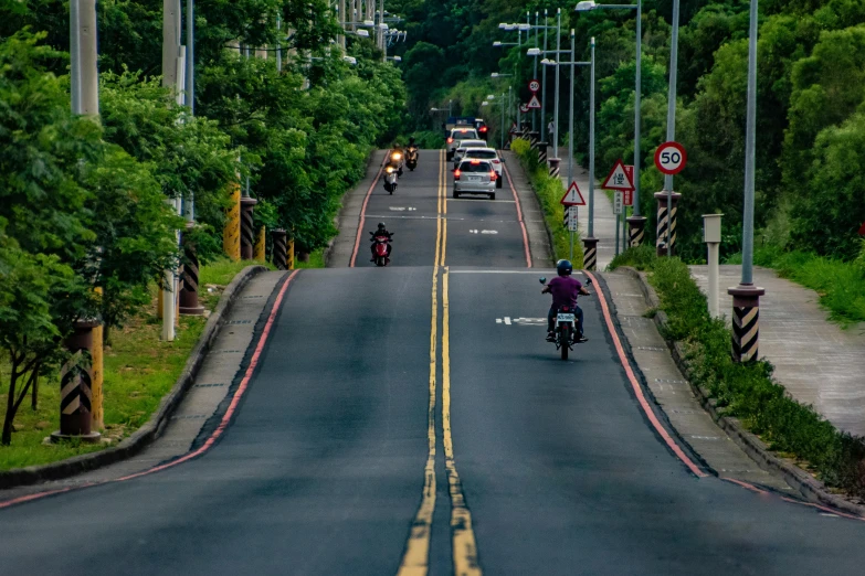 a person riding a motorcycle down a street, by Matt Stewart, pexels contest winner, city of armenia quindio, wide greenways, 5 hotrods driving down a street, taiwan