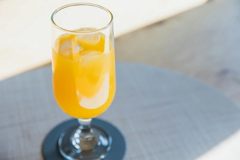 a glass of orange juice sitting on a table, unsplash, renaissance, fan favorite, manuka, grey orange, people drink cocktails