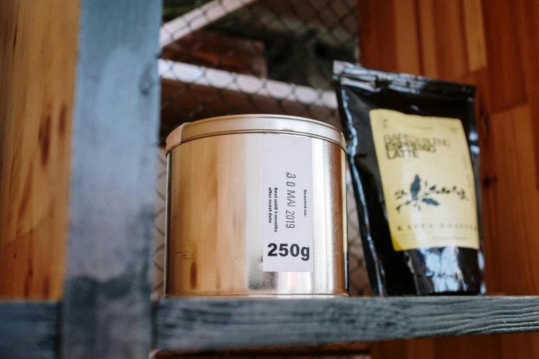 a metal bucket sitting on top of a wooden shelf, inspired by Kanō Shōsenin, unsplash, private press, celebration of coffee products, 25 years old, highly detailed labeled, product introduction photo