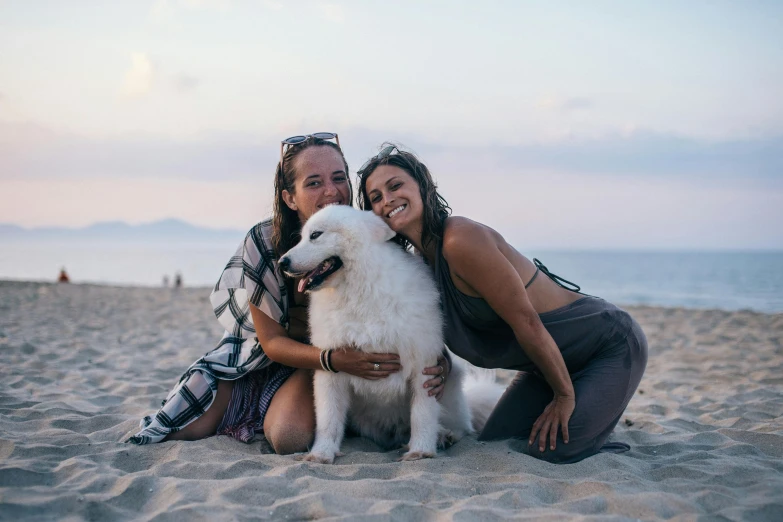 two women pose with a white dog on the beach, pexels contest winner, happening, avatar image, prana, latinas, a group of people