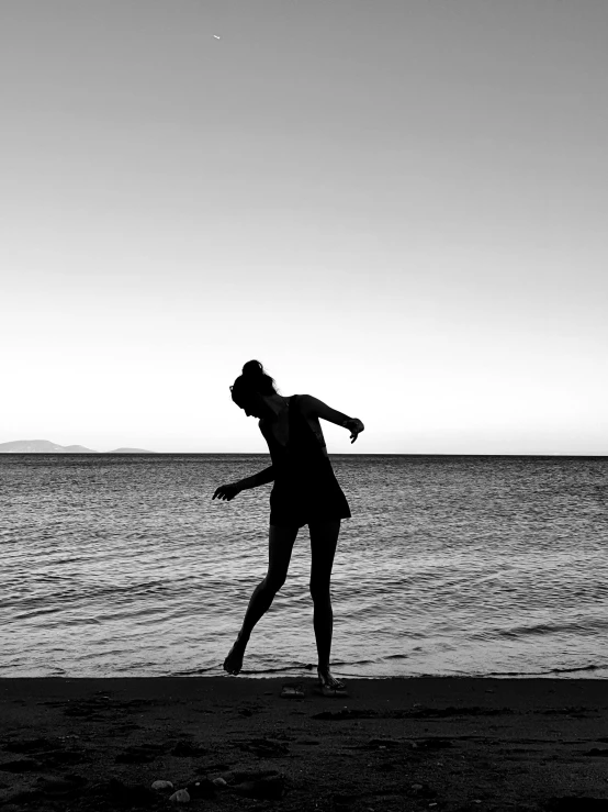 a black and white photo of a woman playing frisbee on the beach, a black and white photo, by Alexis Grimou, unsplash, minimalism, silhouette!!!, classic dancer striking a pose, various posed, posed in profile