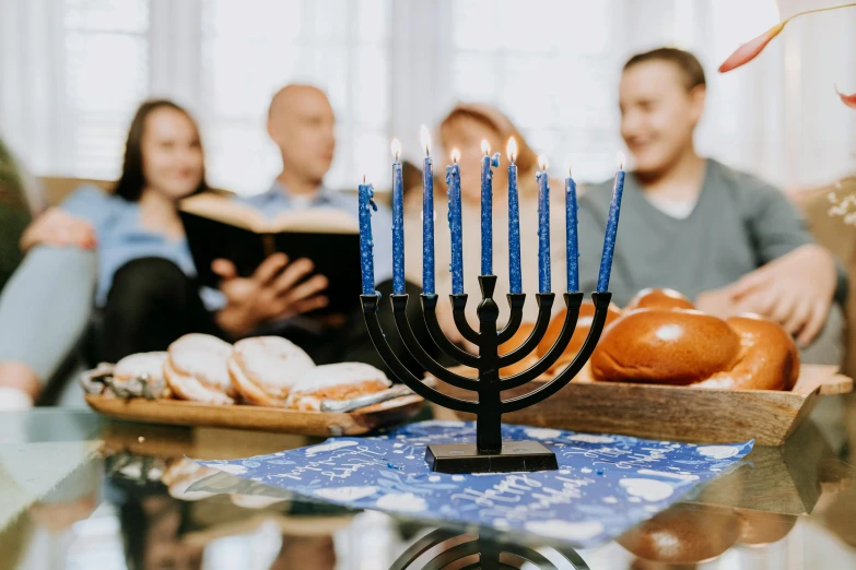 a group of people sitting around a table with a menorah
