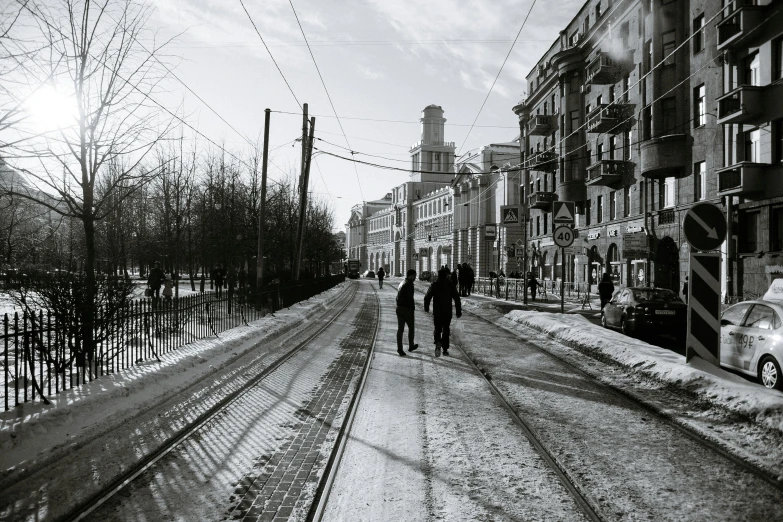 a couple of people walking down a snow covered street, a black and white photo, inspired by Stanislav Zhukovsky, pexels contest winner, socialist realism, dieselpunk norilsk city, trams ) ) ), sunny day time, instagram post