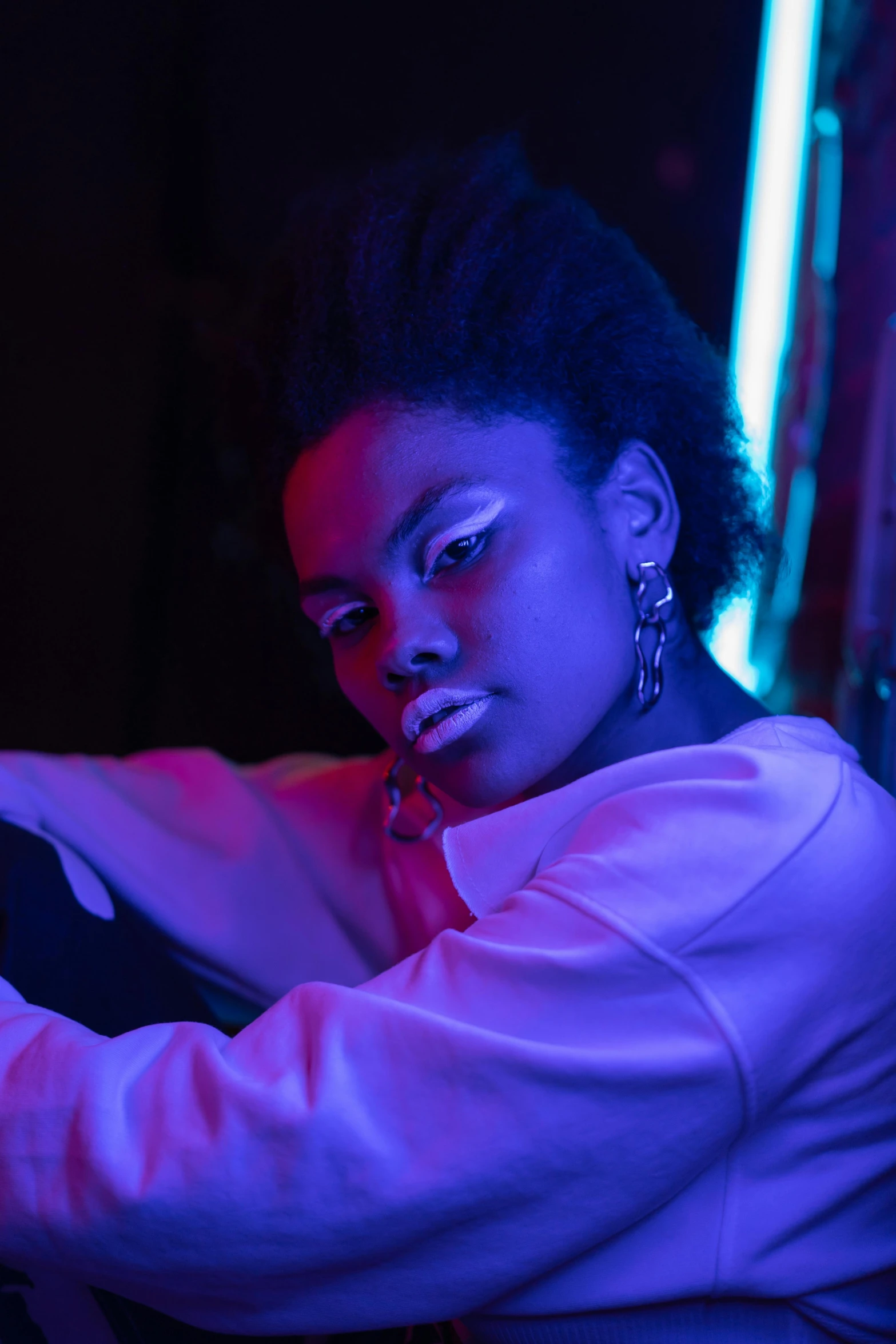 a woman smoking a cigarette in a dark room, an album cover, trending on pexels, afrofuturism, neon purple light, modeling shoot, (night), confident pose