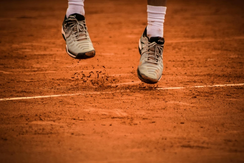 a man standing on top of a tennis court holding a racquet, by Jan Tengnagel, pexels contest winner, kicking up dirt, running shoes, terracotta, zoomed in