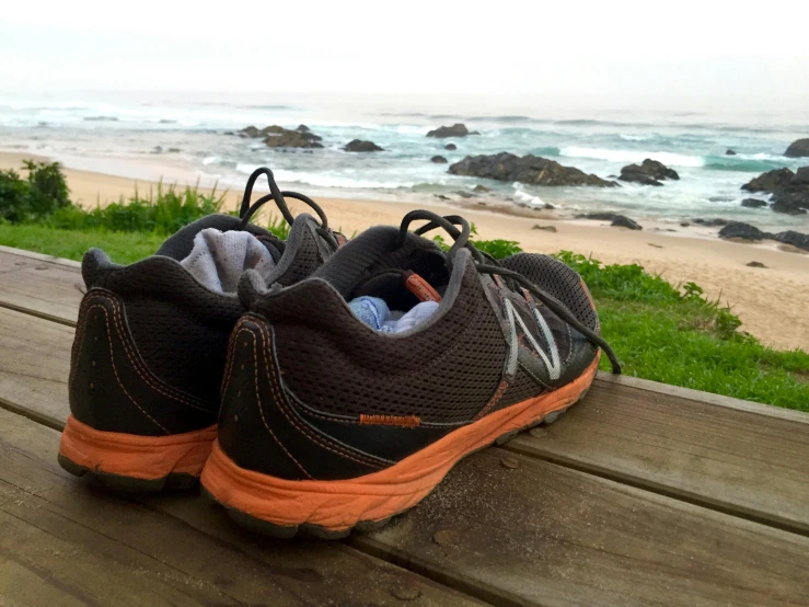 a pair of shoes sitting on top of a wooden bench, south african coast, black and orange, running, grey