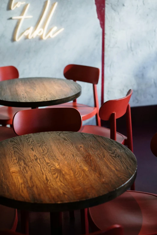 a number of tables and chairs in a room, by Simon Marmion, trending on unsplash, wine red trim, bog oak, circular, cafe