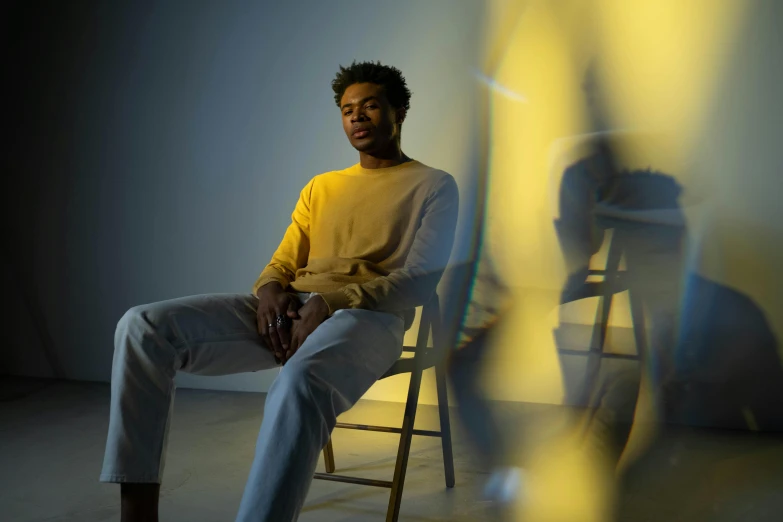 a man sitting on a chair in front of a mirror, inspired by Norman Lewis, pexels contest winner, yellow aura, donald glover, press shot, soft volumetric studio lighting