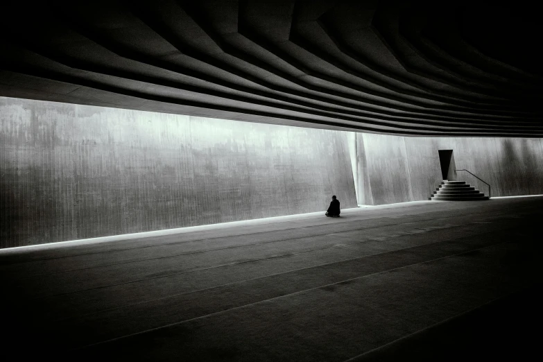 a black and white photo of a person in a dark room, inspired by Zaha Hadid, unsplash contest winner, brutalism, cyberpunk mosque interior, nadav kander, solid concrete, architecture render ”
