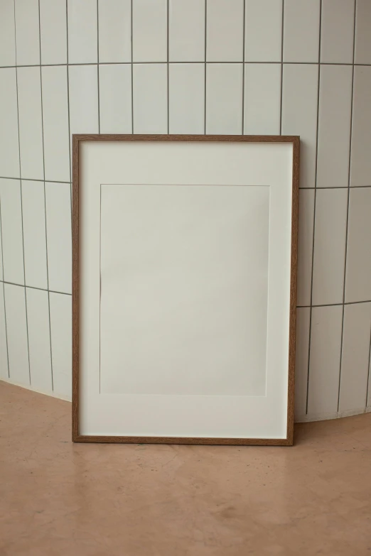 a picture frame on the floor in front of a tiled wall, a poster, by Harvey Quaytman, unsplash, walnut wood, drawn on white parchment paper, ffffound, detailed product image