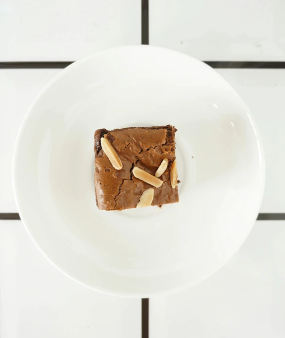 a white plate topped with a piece of brownie, by Jessie Algie, unsplash, fully symmetrical, t - rex, square, islamic