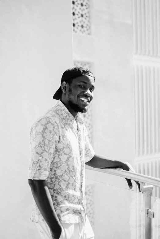 a black and white photo of a man leaning on a railing, by Stokely Webster, smiling sweetly, lil uzi vert, programming, on a pale background