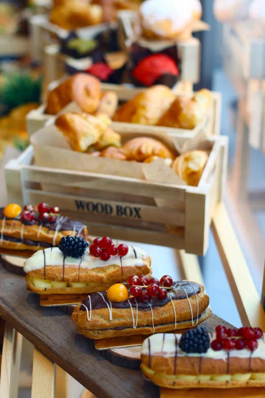 a table topped with lots of different types of pastries, wooden boat, box, close up details, promo