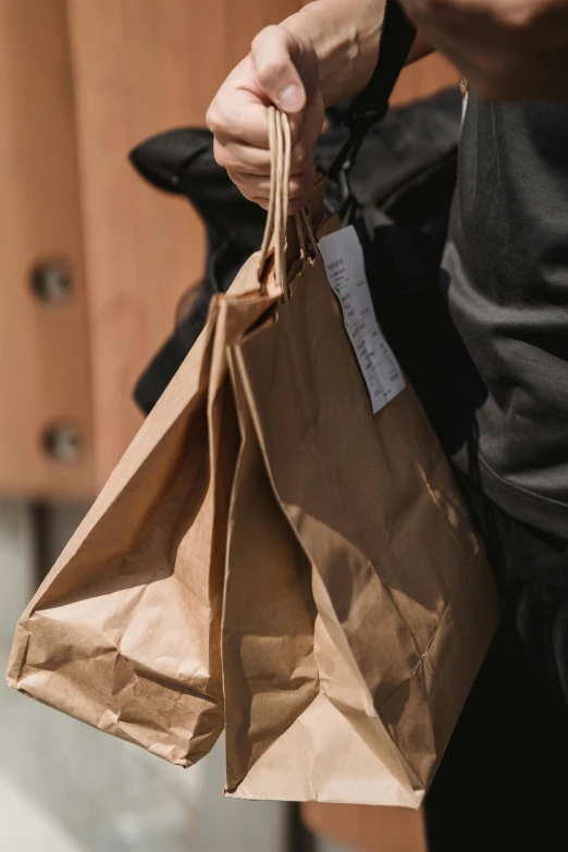 a person holding a brown paper bag in their hand, exiting store, victoria siemer, loosely cropped, brown:-2