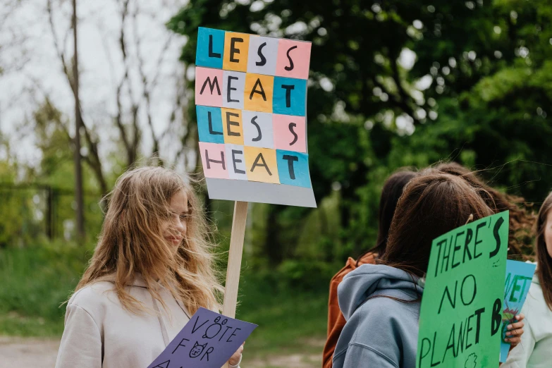 a group of women standing next to each other holding signs, by Julia Pishtar, pexels contest winner, renaissance, heat waves, not a lot of grass, eating meat, politics
