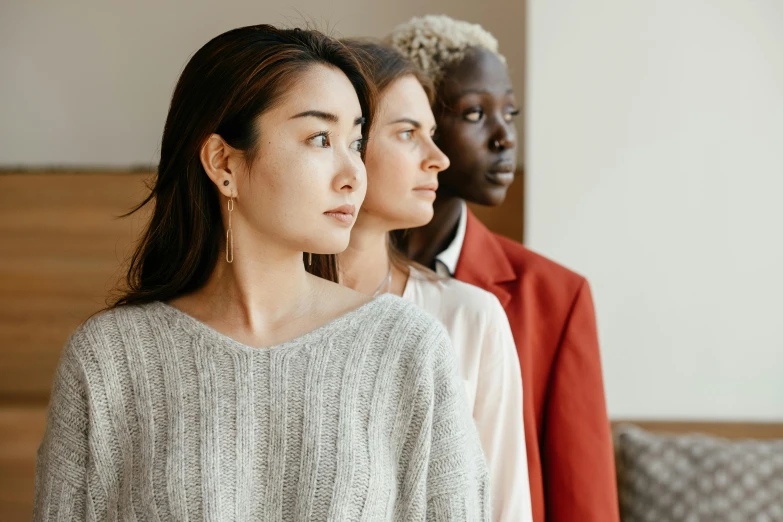 a couple of women standing next to each other, trending on pexels, hyperrealism, ethnicity : japanese, triad of muses, looking from shoulder, wearing casual sweater