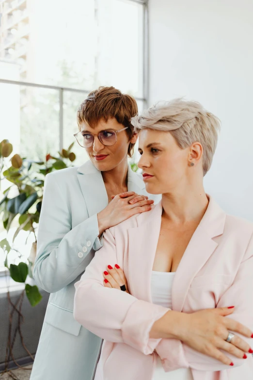 two women standing next to each other in a room, trending on pexels, wearing a suit and glasses, lesbian embrace, scolding, lush vista