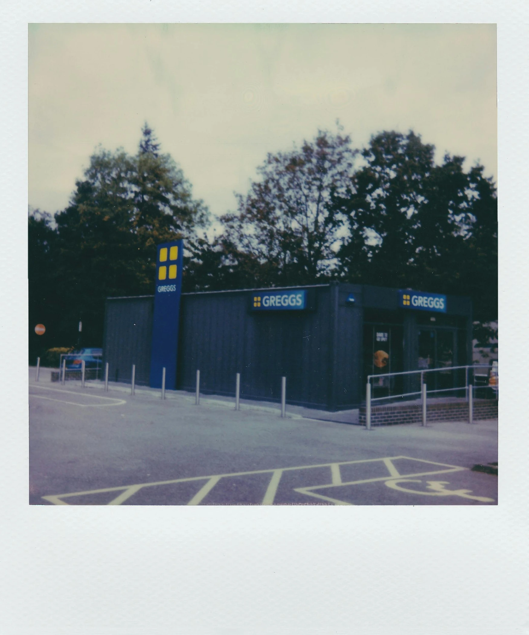 a blue building in a parking lot with trees in the background, a polaroid photo, unsplash, scanned in, ikea, hi - res scan, taken from the high street