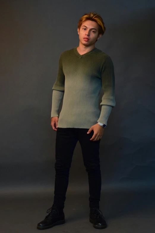 a man standing with his hands in his pockets, a colorized photo, inspired by Nadim Karam, pexels contest winner, gradient green black, grey sweater, full body action pose, wearing v - neck top