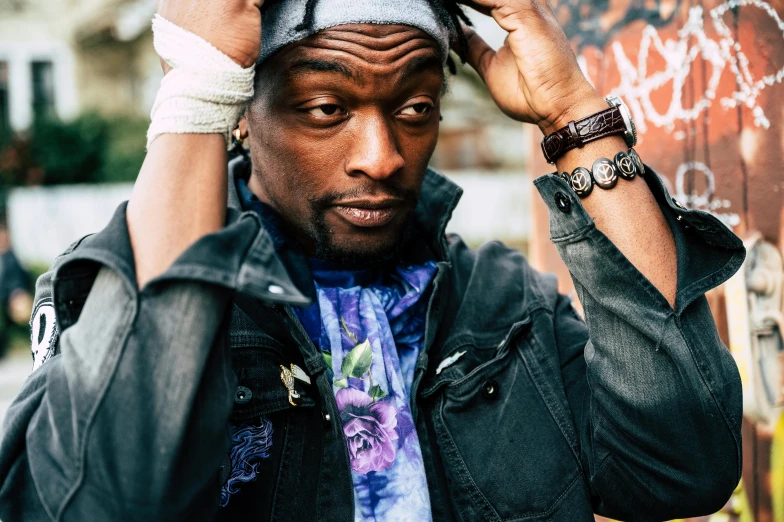 a man standing in front of a graffiti covered wall, a portrait, by Winona Nelson, trending on pexels, lyco art, snoop dogg as a mage, wearing a bandana and chain, kevin hart, 2 1 savage