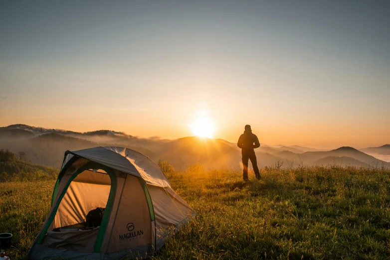 a man standing in a field next to a tent, pexels contest winner, mountain sunrise, avatar image, camping, profile picture