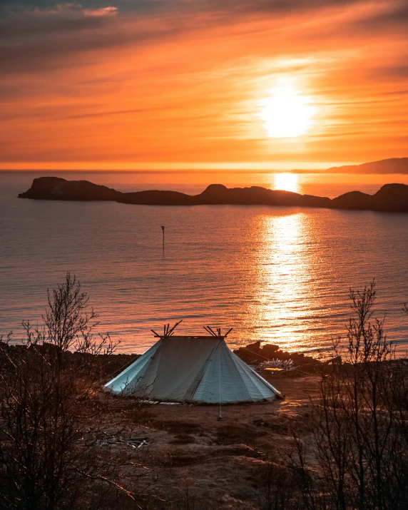 a tent sitting on top of a beach next to a body of water, by Jesper Knudsen, unsplash contest winner, sunset warm spring, viking culture, thumbnail, glamping