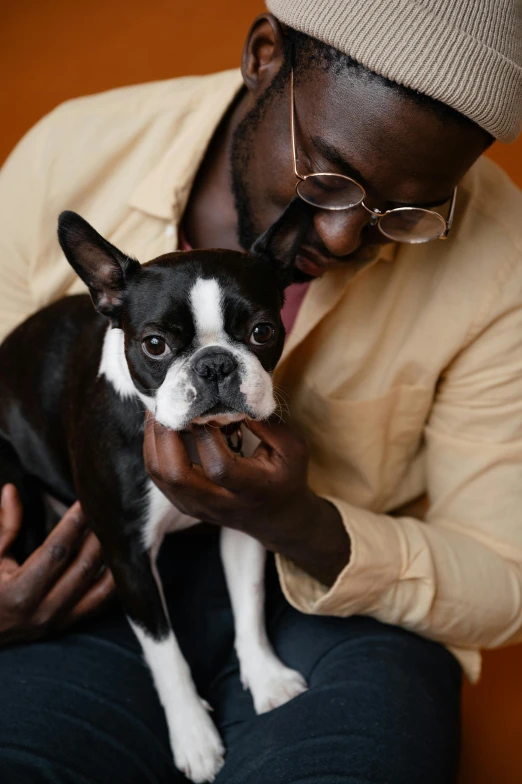 a man holding a small black and white dog, trending on unsplash, renaissance, black man, caring fatherly wide forehead, lgbtq, brown