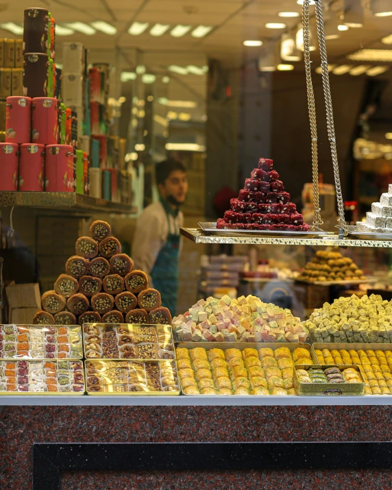 a display case filled with lots of different types of pastries, a mosaic, trending on unsplash, hurufiyya, orientalist, panorama shot, candy decorations, seen from outside