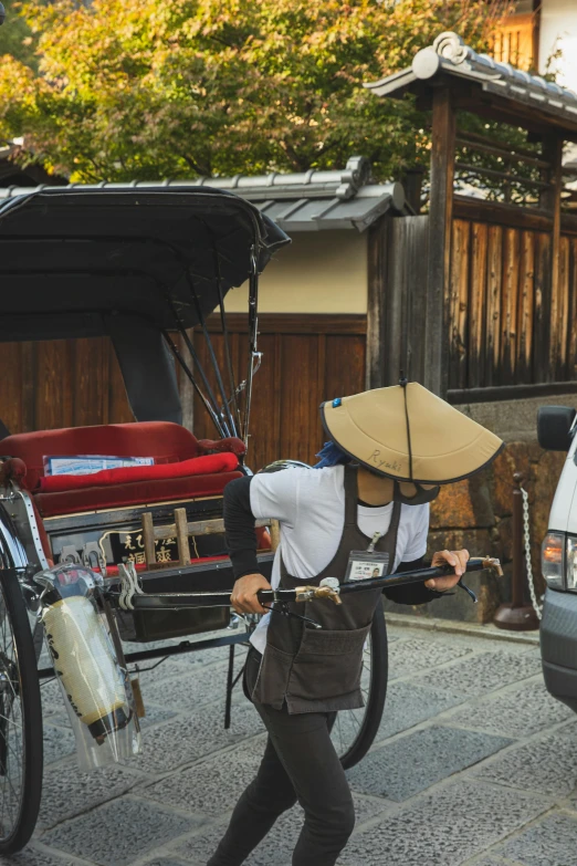 a man walking down a street next to a car, inspired by Takeuchi Seihō, unsplash, peaked wooden roofs, wearing an elaborate helmet, cart, rear view