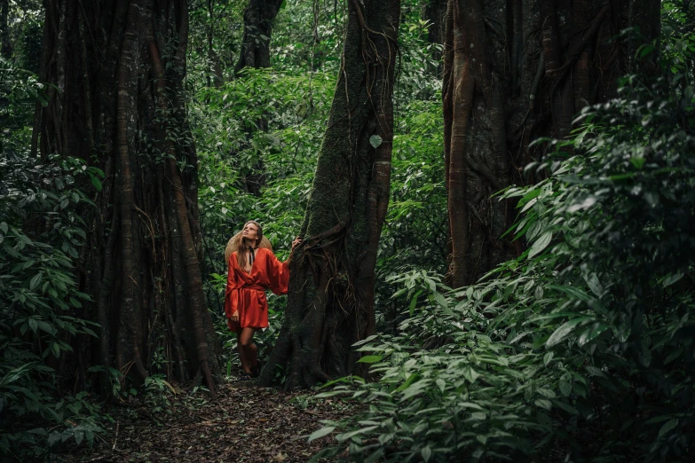 a woman standing in the middle of a forest, inspired by Steve McCurry, sumatraism, orange robe, avatar image