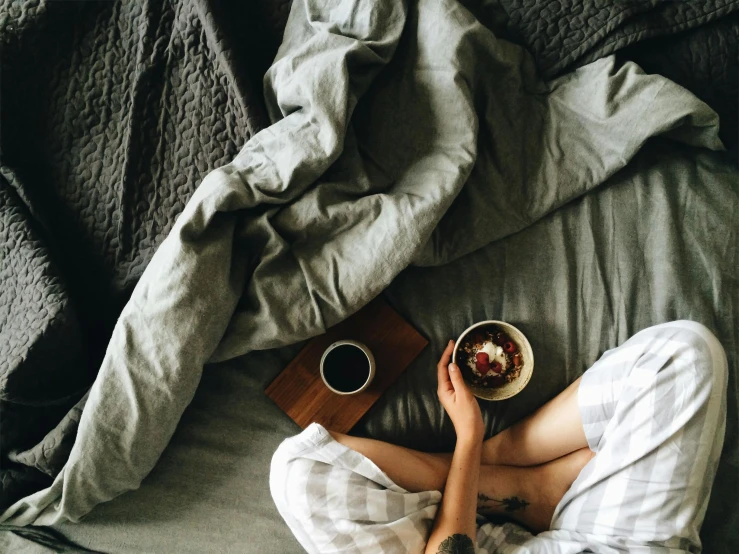 a person laying in bed with a bowl of food, inspired by Elsa Bleda, trending on pexels, cold brew coffee ), grey, cozy bed, intricately defined