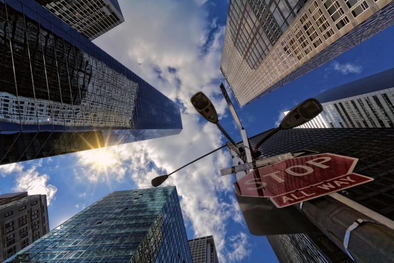 a stop sign in the middle of a city, a picture, by Adam Marczyński, pexels contest winner, photorealism, sky scrapers, volumetric light from below, manhatten on top of skyscrapers, mies van der rohe