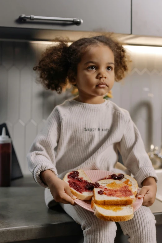 a little girl sitting on a counter holding a sandwich, by Nina Hamnett, pexels contest winner, food styling, eva elfie, meaty, on kitchen table