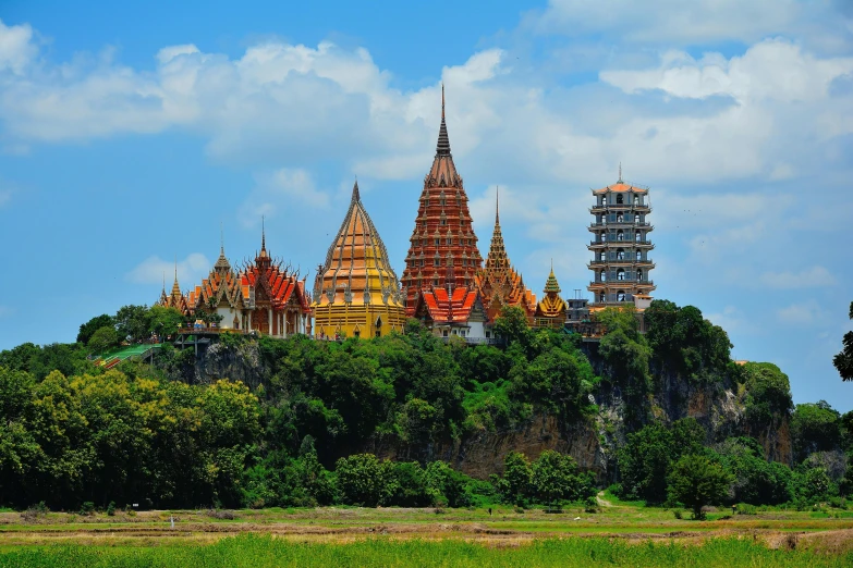 a large building sitting on top of a lush green hillside, an album cover, pexels contest winner, thai temple, majestic spires, multicoloured, thumbnail