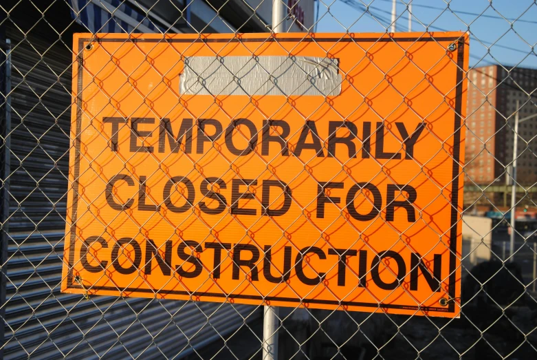 a close up of a sign on a fence, flickr, temporary art, construction site, getty images, orange, unfortunate