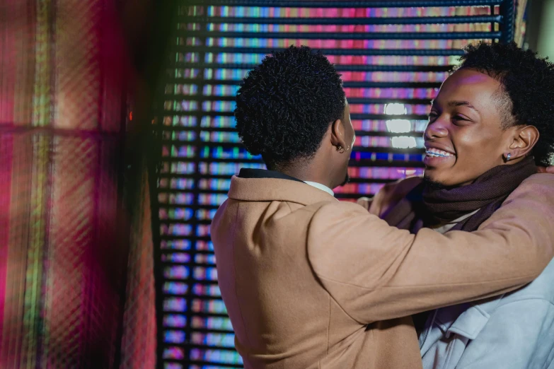 a couple of people standing next to each other, trending on pexels, happening, colourful dramatic lighting, smiling and dancing, lesbian embrace, ( ( dark skin ) )