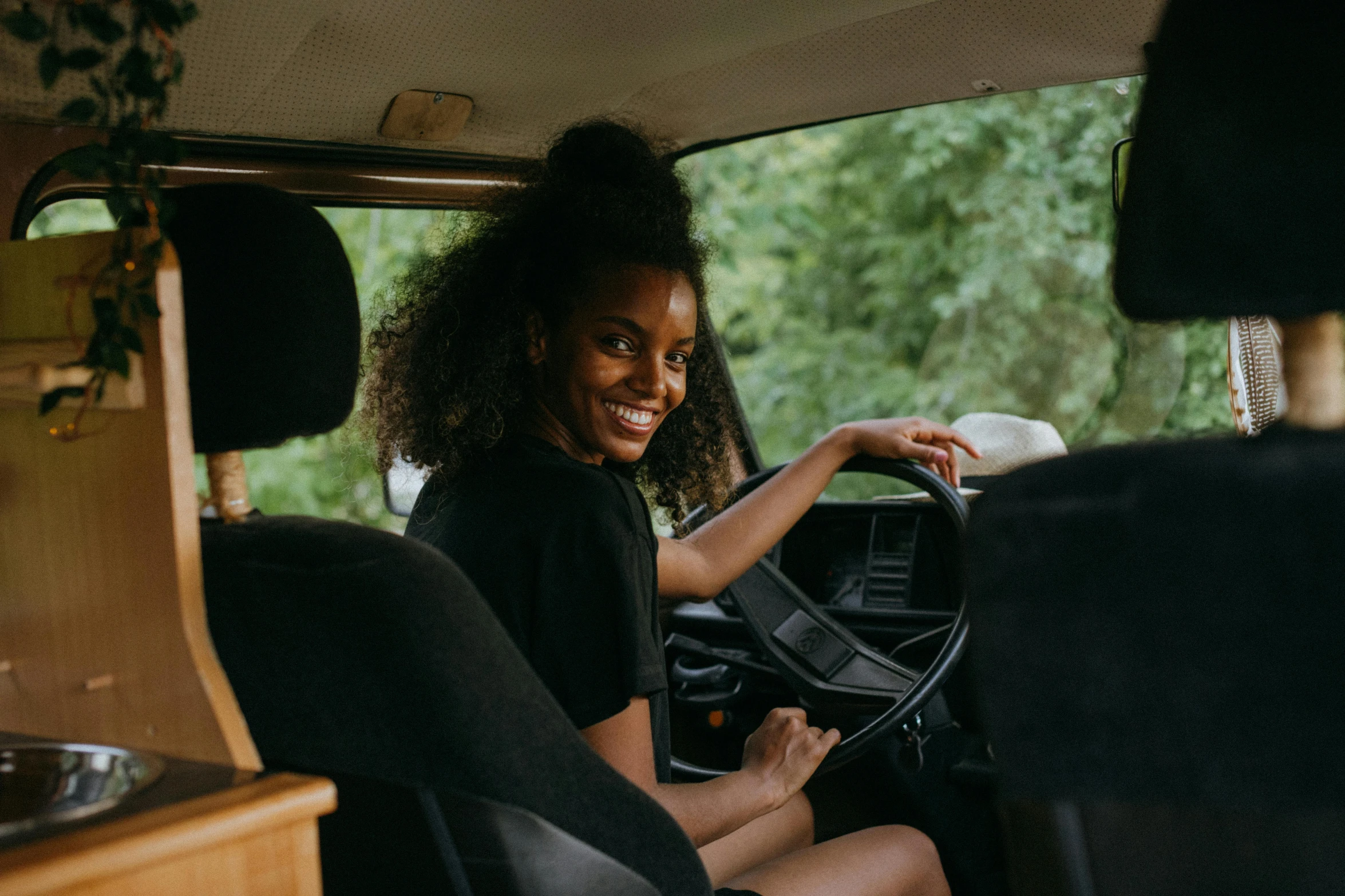 a woman sitting in the driver's seat of a van, pexels contest winner, happening, black young woman, ivory and ebony, welcoming grin, classic gem