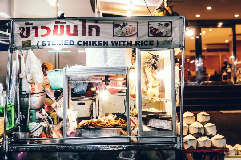 a food cart sitting on the side of a street, by Julia Pishtar, unsplash, chicken, in style of thawan duchanee, at the counter, lit from the side