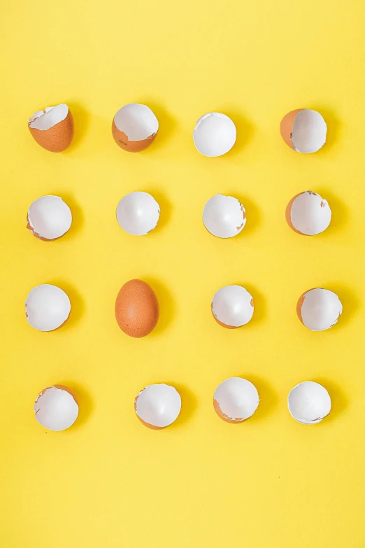 a group of eggs on a yellow background, an album cover, trending on pexels, broken, knolling, demur, 64x64