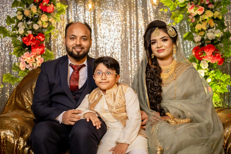 a man sitting next to a woman and a child, a picture, by Riza Abbasi, pexels contest winner, hurufiyya, posing elegantly over the camera, wedding, slightly pixelated, proud looking