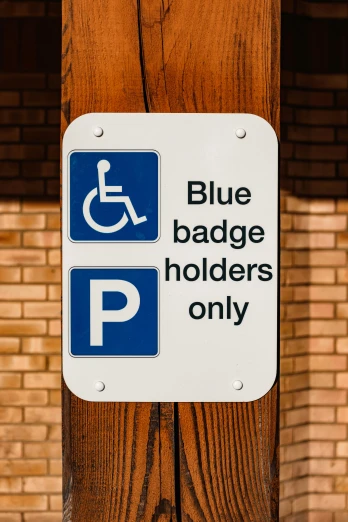 a blue and white sign on a wooden pole, sitting in a wheelchair, badge, holographic plastic, most blues