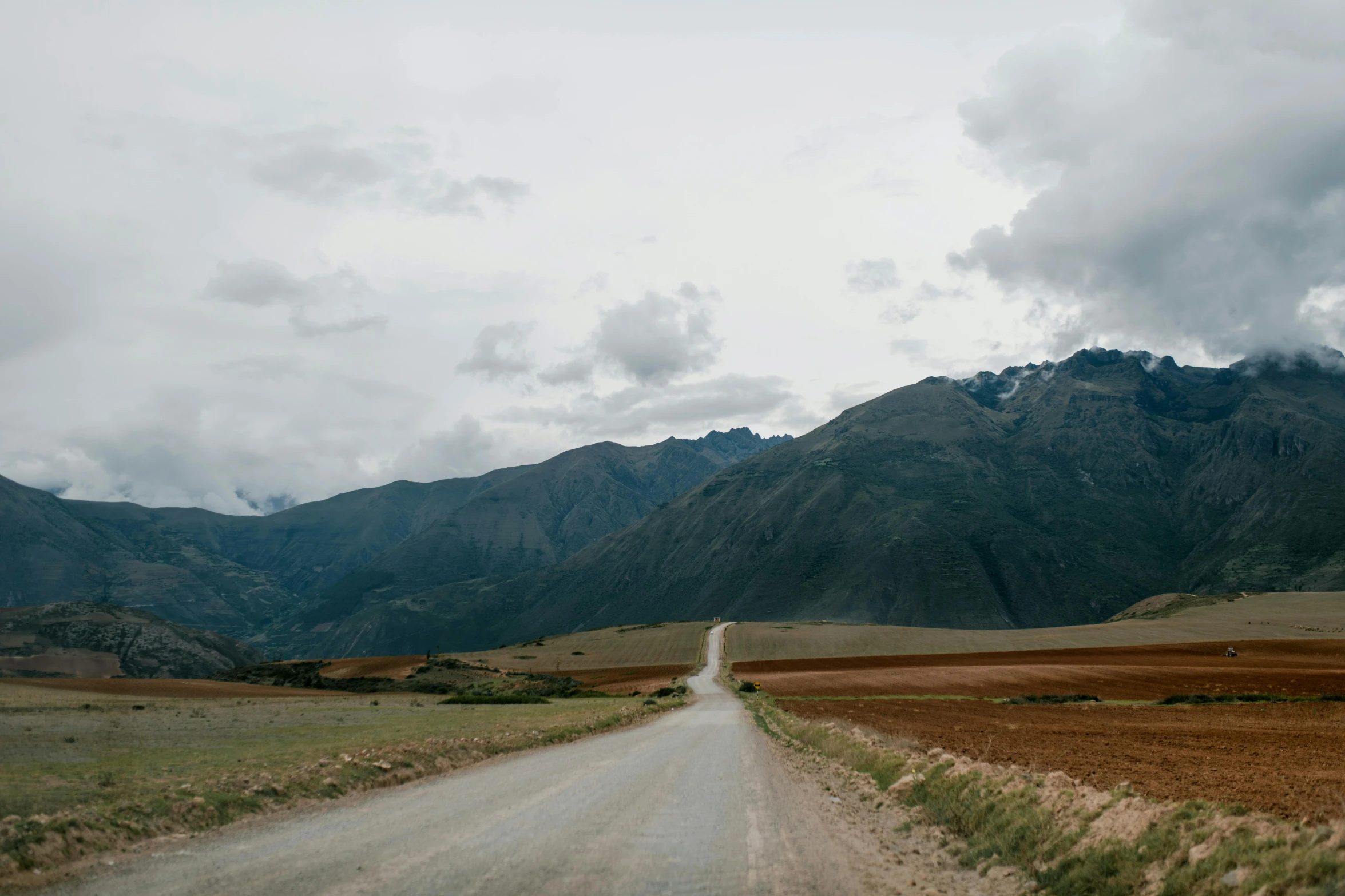 a dirt road with mountains in the background, an album cover, pexels contest winner, quechua, background image, slight overcast weather, corduroy road