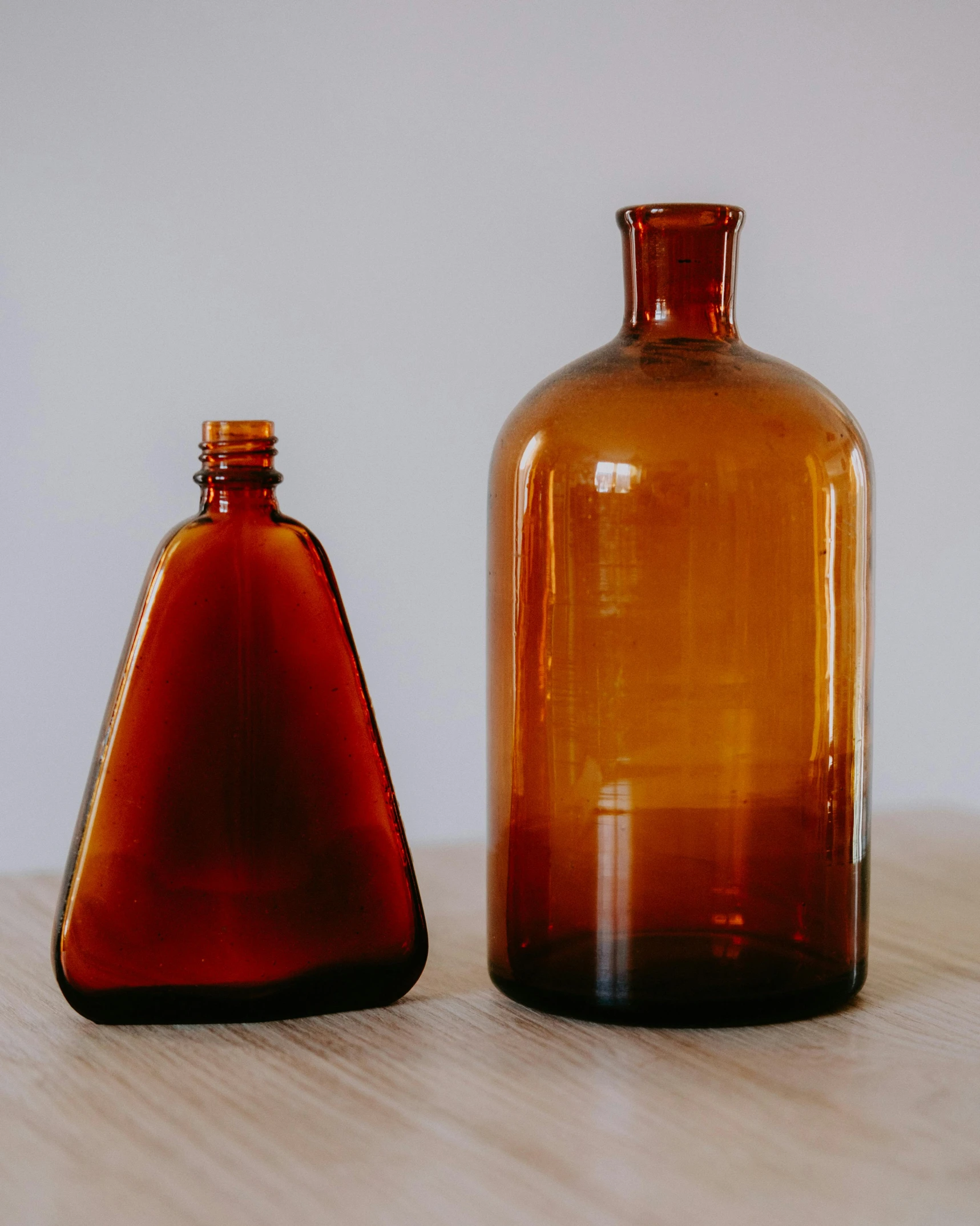 a couple of brown bottles sitting on top of a wooden table, a still life, unsplash, scientific glassware, ochre, angled, close-up product photo