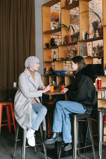 two women sitting at a table in a coffee shop, trending on pexels, realism, beanie, hana alisa omer, full length shot, gif