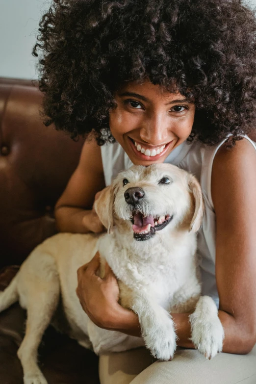 a woman sitting on a couch holding a dog, playful smile, gold, zoomed in, digital image