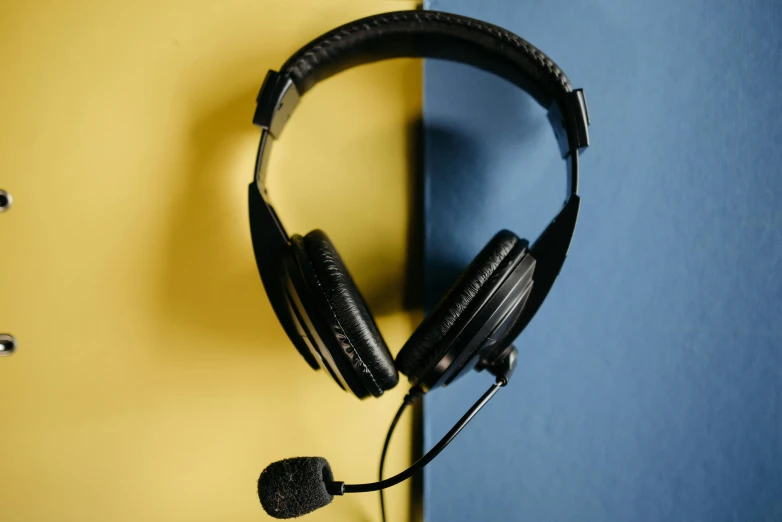 a pair of headphones hanging on a wall, pexels, hurufiyya, avatar image, black and yellow, sitting in front of a microphone, wearing headset