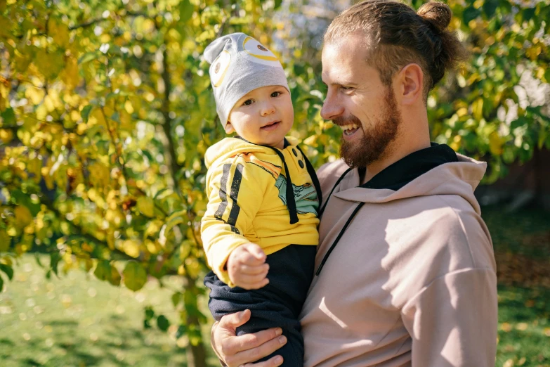 a man holding a baby in his arms, pexels contest winner, wearing a tracksuit, avatar image, anato finnstark and kelogsloops, sunny day time