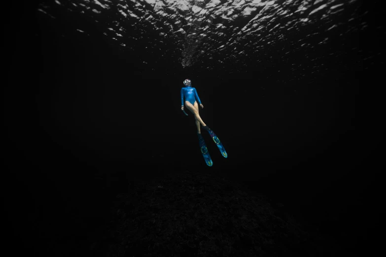 a woman in a wetsuit and flippers swims under the surface of the water, by Daniel Gelon, unsplash contest winner, conceptual art, dark blue skin, fishing, descent, clematis in the deep sea